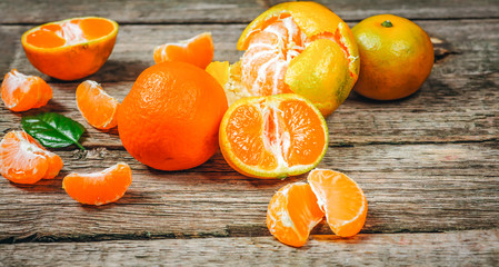 Tangerines (mandarins, clementines, citrus fruits) with leaves over rustic wooden background with copy space