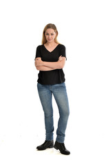 full length portrait of blonde girl wearing black shirt and jeans, standing pose isolated on a white background.