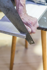 man sawing a board with a hacksaw