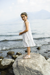 portrait of a little girl standing on a rock on the shore of Lake Maggiore