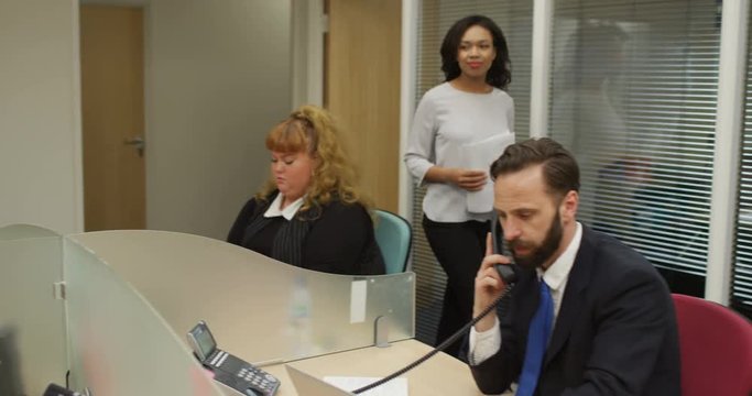 4K Happy business team getting on with their jobs in modern city office
