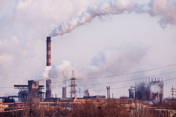 smoke stacks in a working factory emitting steam, smog and air pollution.