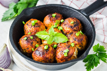 Greek lamb baked meatballs in cast iron skillet on white stone background. Selective focus, copy space.