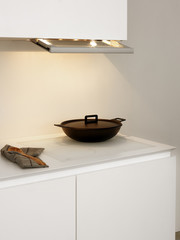 black pot cooking on a white induction top of a white kitchen.