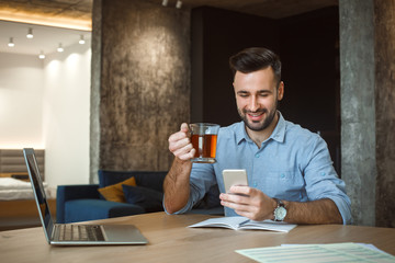 Bachelor man daily routine working from home single lifestyle concept drinking tea browsing smartphone