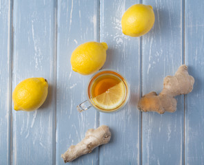 A cup of ginger tea with lemon on a wooden background.