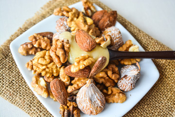Almonds, walnuts and dried figs and honey on a white plate on a background sacking.