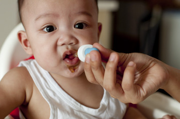 A baby boy is drinking his vitamins using a dropper