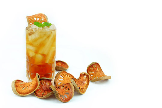 Iced bael fruit juice with sliced dry bael fruit on white background.