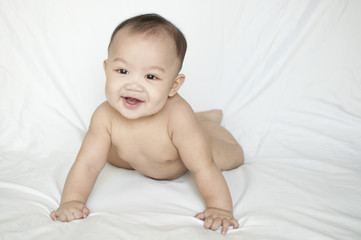 A nude portrait of a smiling baby boy indoor