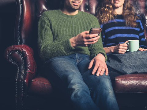 Man on sofa showing woman his phone