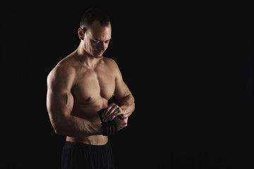 Fototapeta premium Athletic boxer wrapping hands with boxing bandage