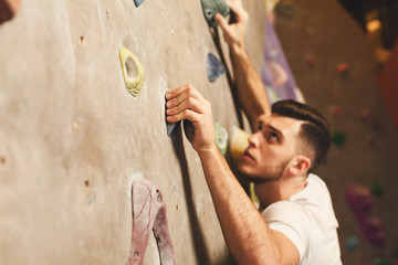 Obraz na płótnie Canvas Young man climbing artificial rock wall at gym