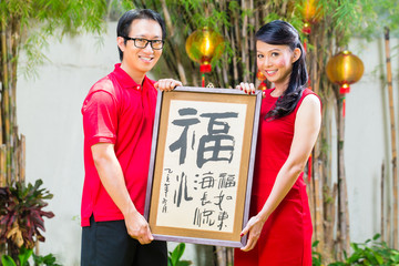 Couple celebrate Chinese new year with traditional gift, wearing red