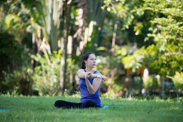 Young woman practicing yoga in the park outdoor. Concept of healthy lifestyle and relaxation.