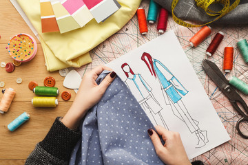 Female fashion designer working with fabric sample and drawn illustration