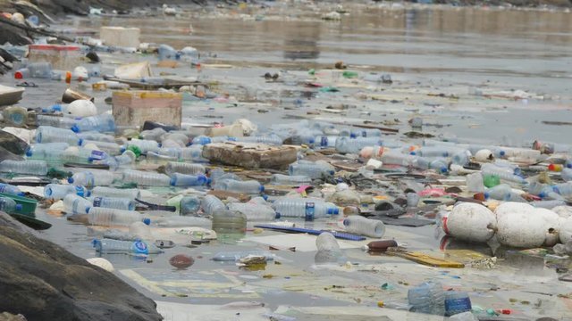 Environmental pollution. Plastic bottles, bags, trash in river, lake. Rubbish and pollution floating in water