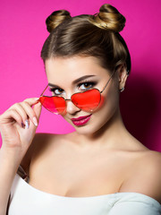 Young woman looks over heart shaped glasses