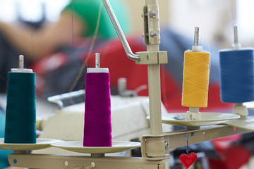 Closeup of coils with colored threads on sewing machine overlock.