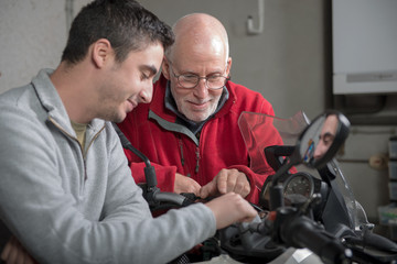 father and son repairing motorcycle