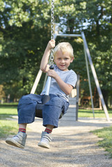 Child boy rides on Flying Fox play equipment in a children's playground, summertime
