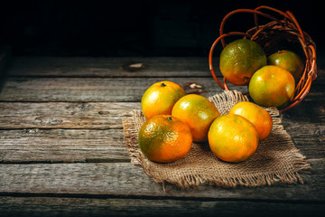 Tangerines (mandarins, clementines, citrus fruits) with leaves over rustic wooden background with copy space