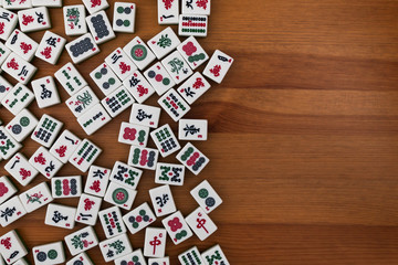 White-green tiles for mahjong on a brown wooden background. Empty place in the rigth.
