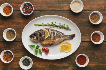Whole grilled dorado with lemon slices on table