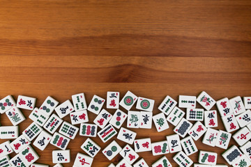 White-green tiles for mahjong on a brown wooden background. Empty space above