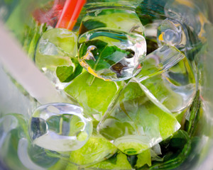 Fototapeta na wymiar Close-up macro mojito in glass with cocktail straw, ice mixed, mint leaves and lime top view. Fresh summer abstract background.