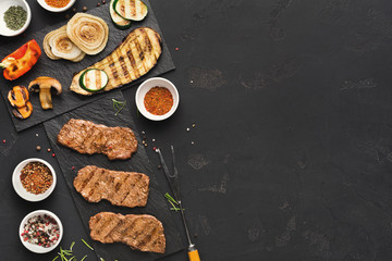 Small pork steaks on black background