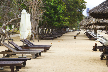 lonely sandy beach with beach chairs and umbrellas near the sea with big waves