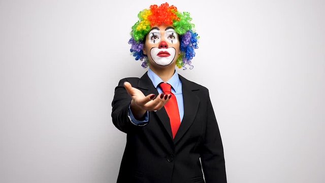 Clown in business suit throwing up a coin in slow motion