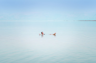 Fototapeta na wymiar Girl relaxing in the water of Dead Sea.