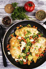 fried chicken fillet with spices in a frying pan and vegetables