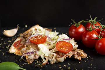Slace of kebap pizza made with minced meat, cabbage, tomato and dried oregano