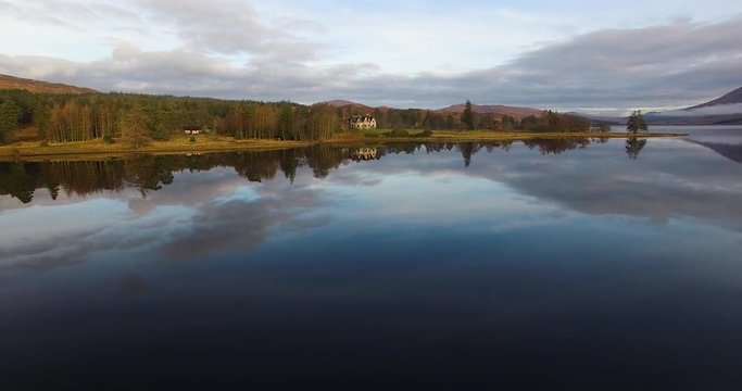 aerial footage of flying over a calm mirrorlike scottish loch in the remote highlands of scotland at loch tulla