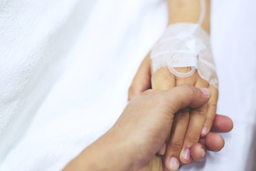 close up focus on the Shake hands of a patient sick encourage encouragement on the bed in hospital ward.	