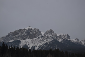 Fototapeta na wymiar Snow Covered Rocky Mountains with Hazy Grey Sky
