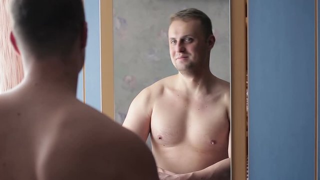 Funny narcissist guy straining his muscles in front of the mirror