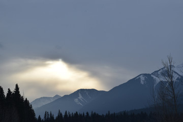 Sunlight being blocked by clouds over snowy mountain peaks