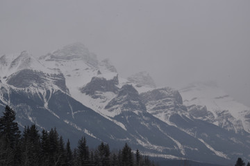 Fototapeta na wymiar Snow Covered Rocky Mountains with Hazy Grey Sky
