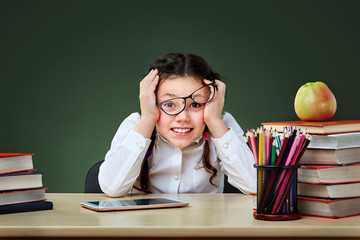 Girl with books points on green chalkboard