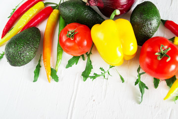 Set of fresh vegetables on a light background: tomatoes, peppers, chili, avocado, greens, onion. The concept of natural healthy eating, vegetarianism, vitamins.