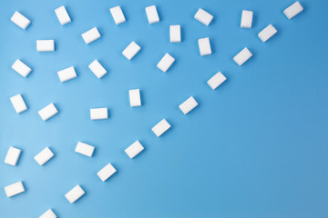 White sugar cubes arranged in diagonal lines on blue background