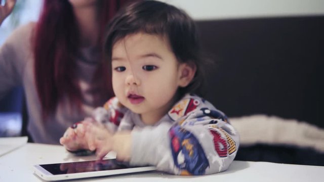 An adorable cute asian toddler boy is playing games on cellphone.