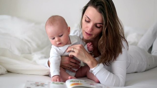 Young mom reading a book to her baby boy, mother read book