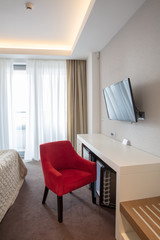 Naklejka na ściany i meble red armchair near white table with TV set on background window