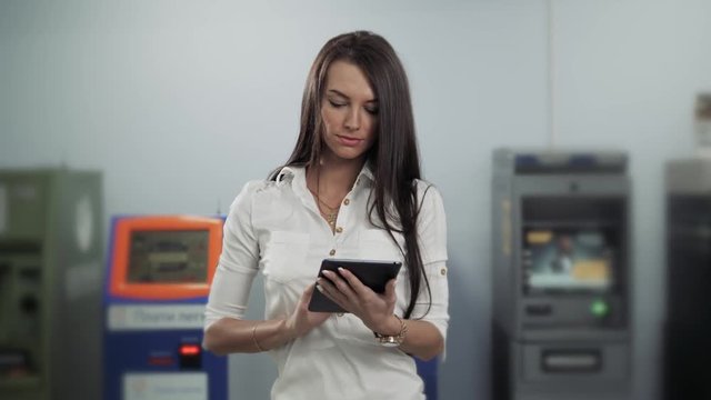 Businesswoman use digital tablet on ATM background, bank work, business woman withdrawal