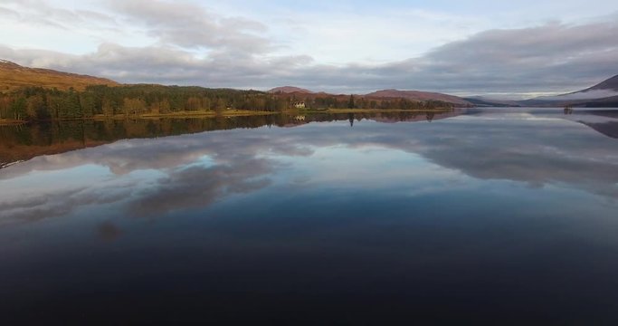 aerial footage of flying over a calm mirrorlike scottish loch in the remote highlands of scotland at loch tulla